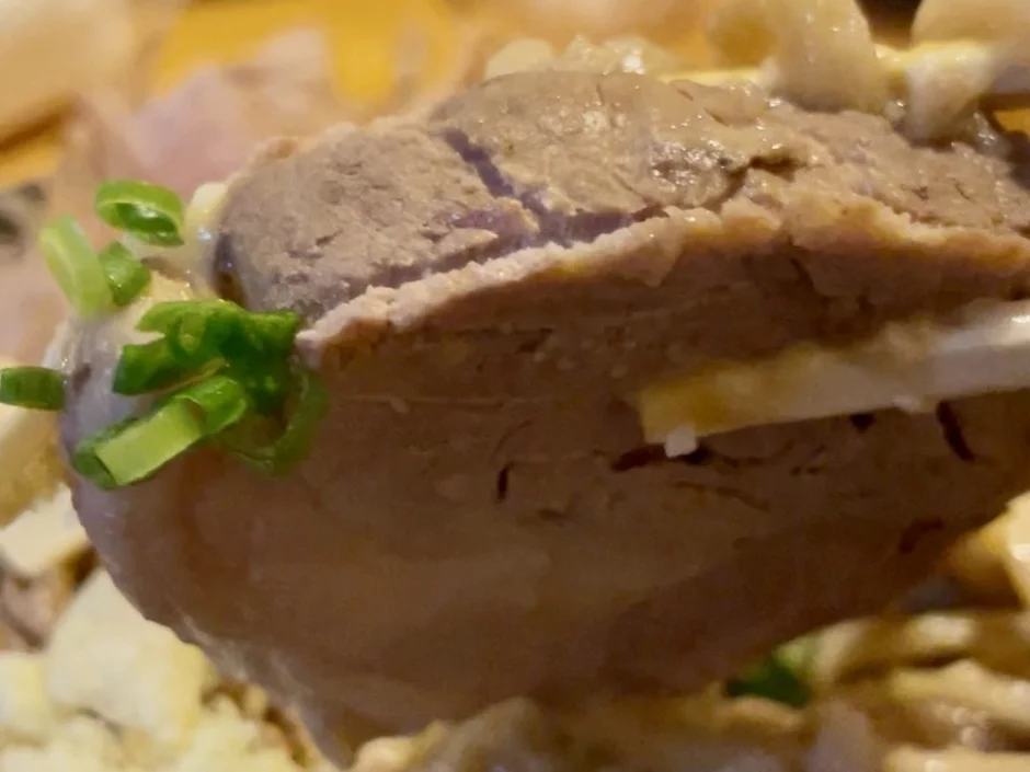 箸で持ち上げられたチャーシュー