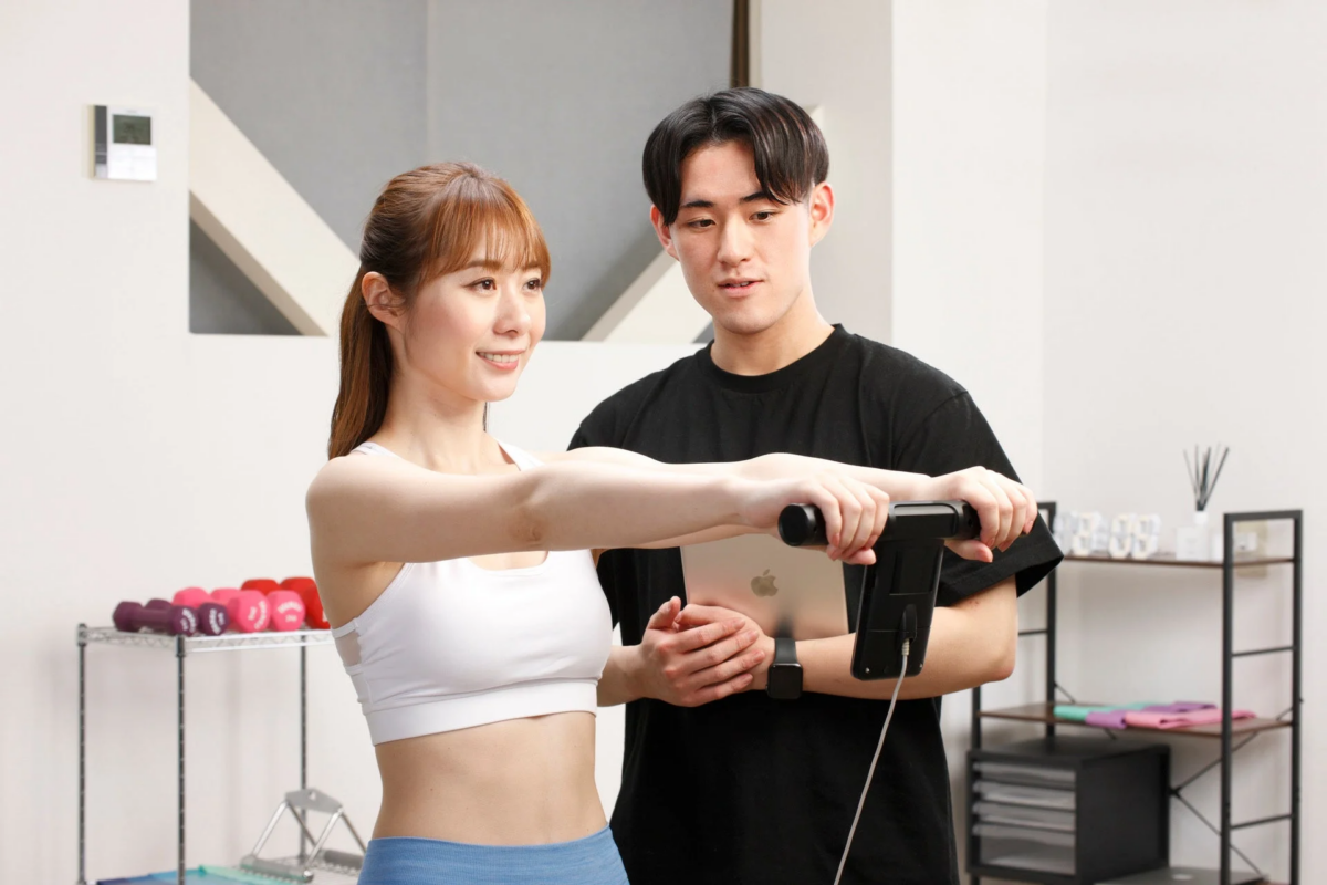 トレーナーと体組成計で測定する女性