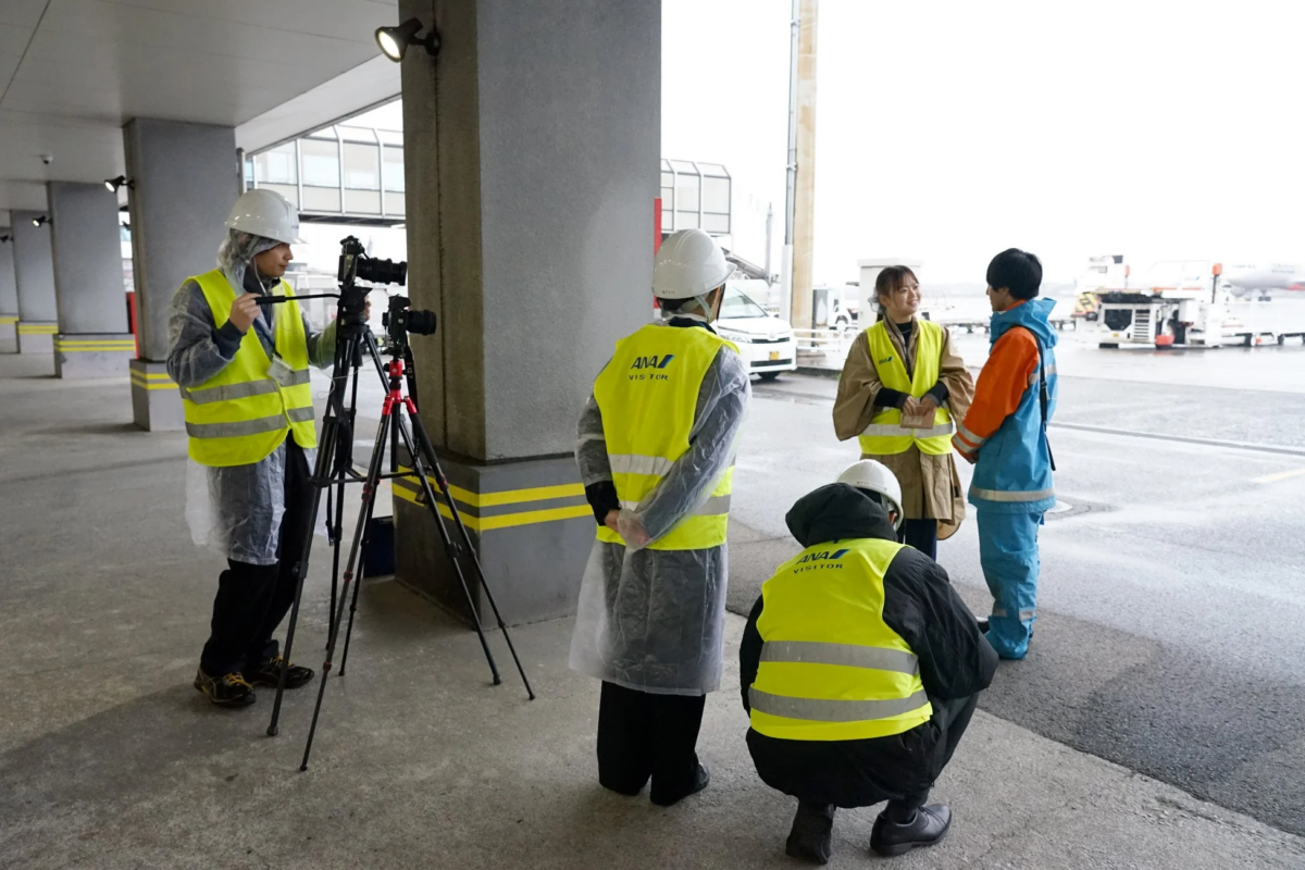 空港での作業員と取材クルー