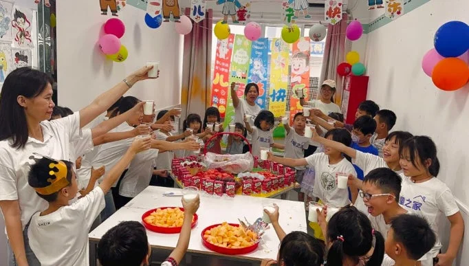 子供たちが大人と一緒にグラスを掲げ、乾杯しているお祝いの様子