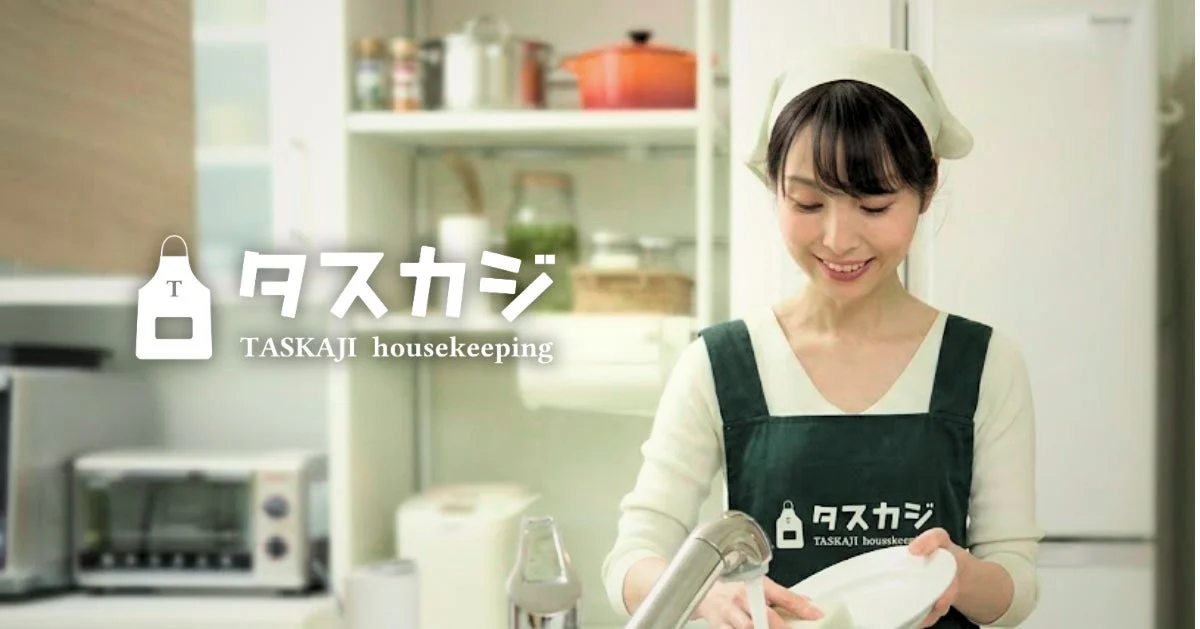 キッチンで笑顔で皿洗いをする女性