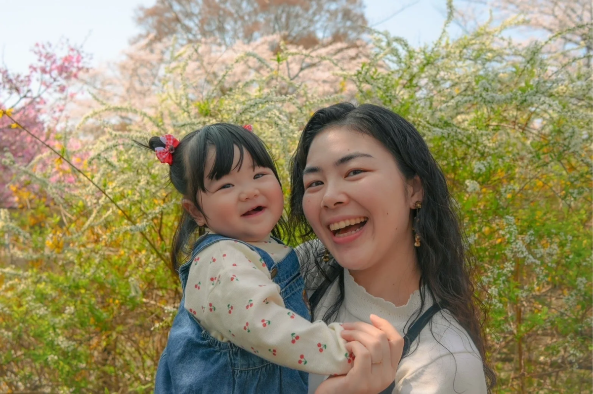 春の屋外で赤ちゃんを抱き満面の笑みを浮かべる親子