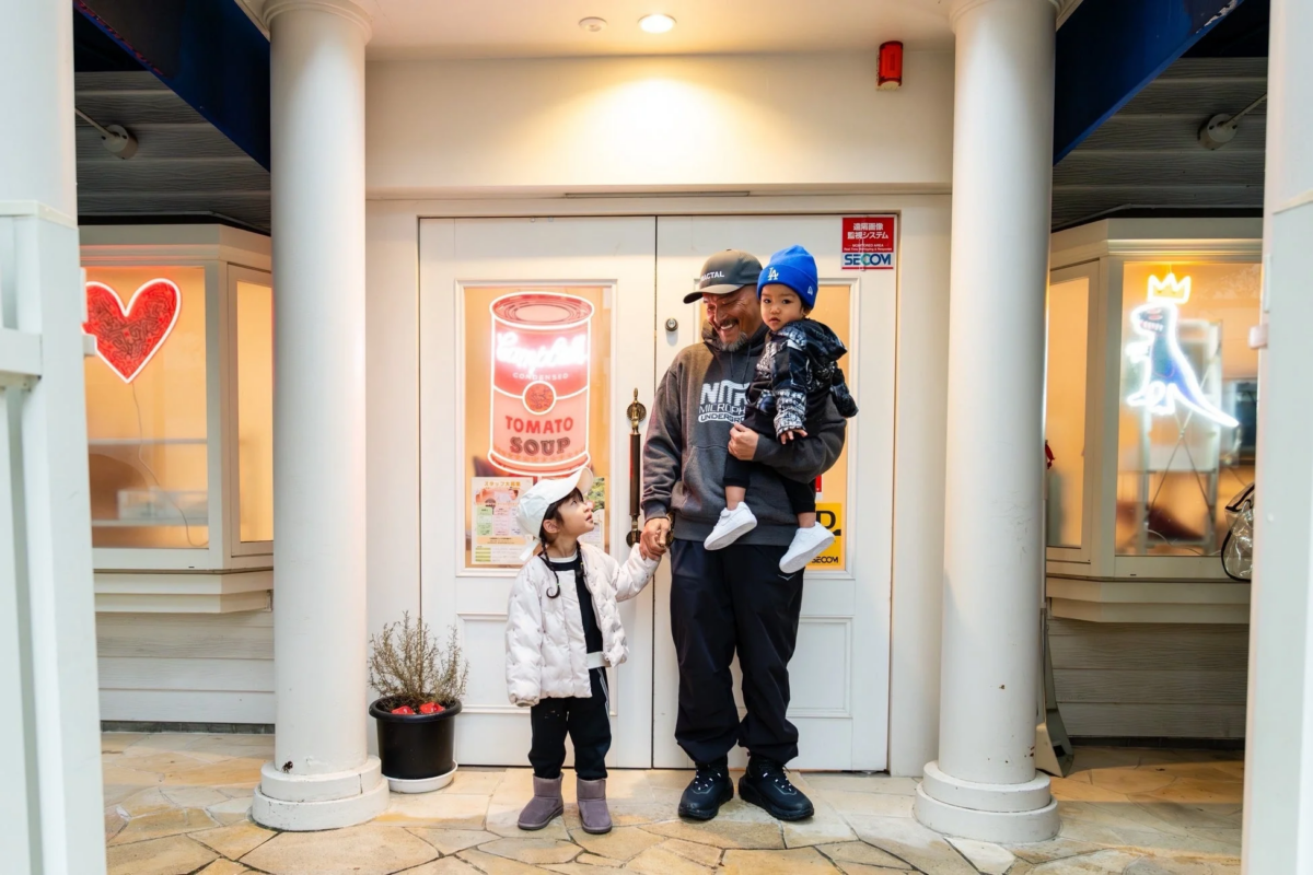 店舗の入り口前に立つ家族