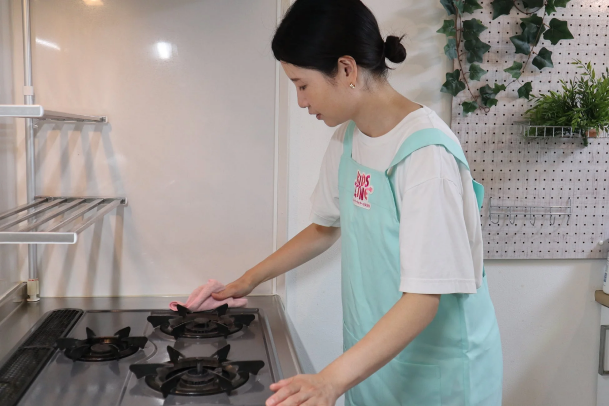 キッチンでガスコンロを丁寧に拭き掃除する女性