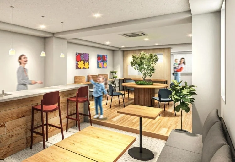 明るくモダンな空間に、バーカウンター、様々なテーブル席、ソファが配置されたラウンジのような場所です。子供や親子連れが過ごしており、リラックスした雰囲気が漂っています。