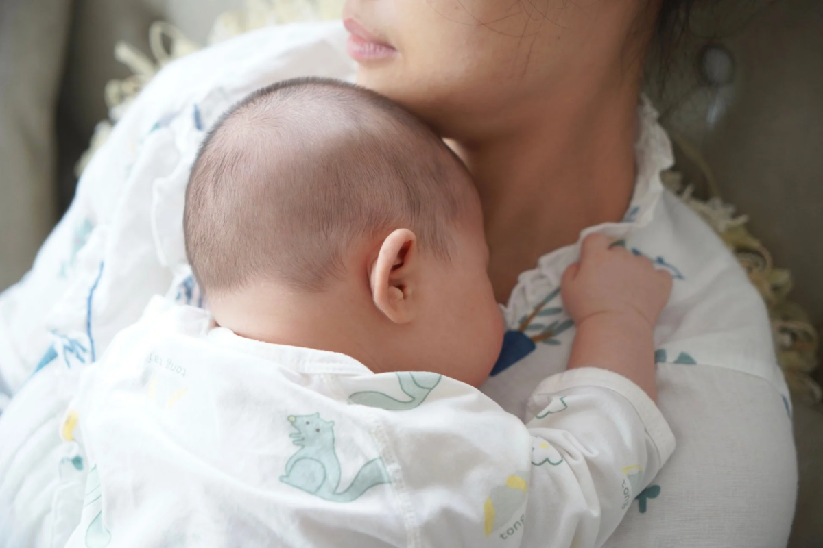 母親の肩に抱かれて安らかに眠る赤ちゃんの姿
