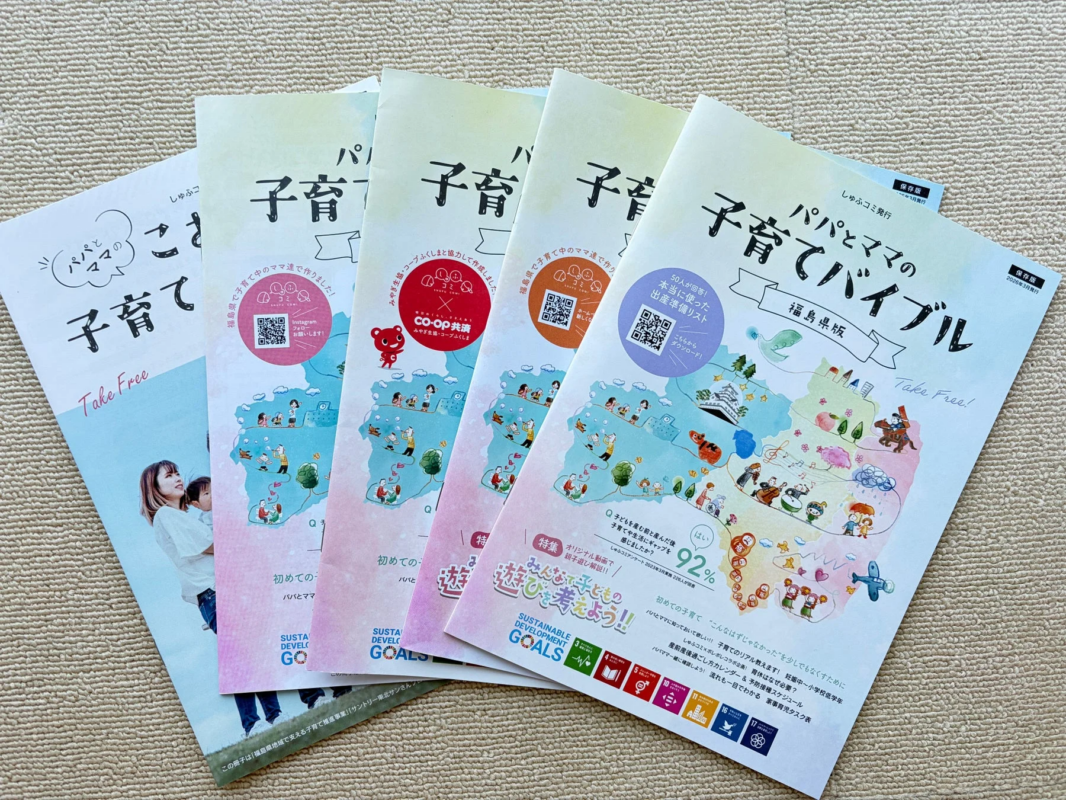 複数の「パパとママの子育てバイブル」フリーマガジンが積み重ねて置かれています。手前の福島県版は、出産準備リスト、子育てのギャップ、親子遊び、SDGs、育休、スケジュールなど、子育てに必要な情報が満載です。